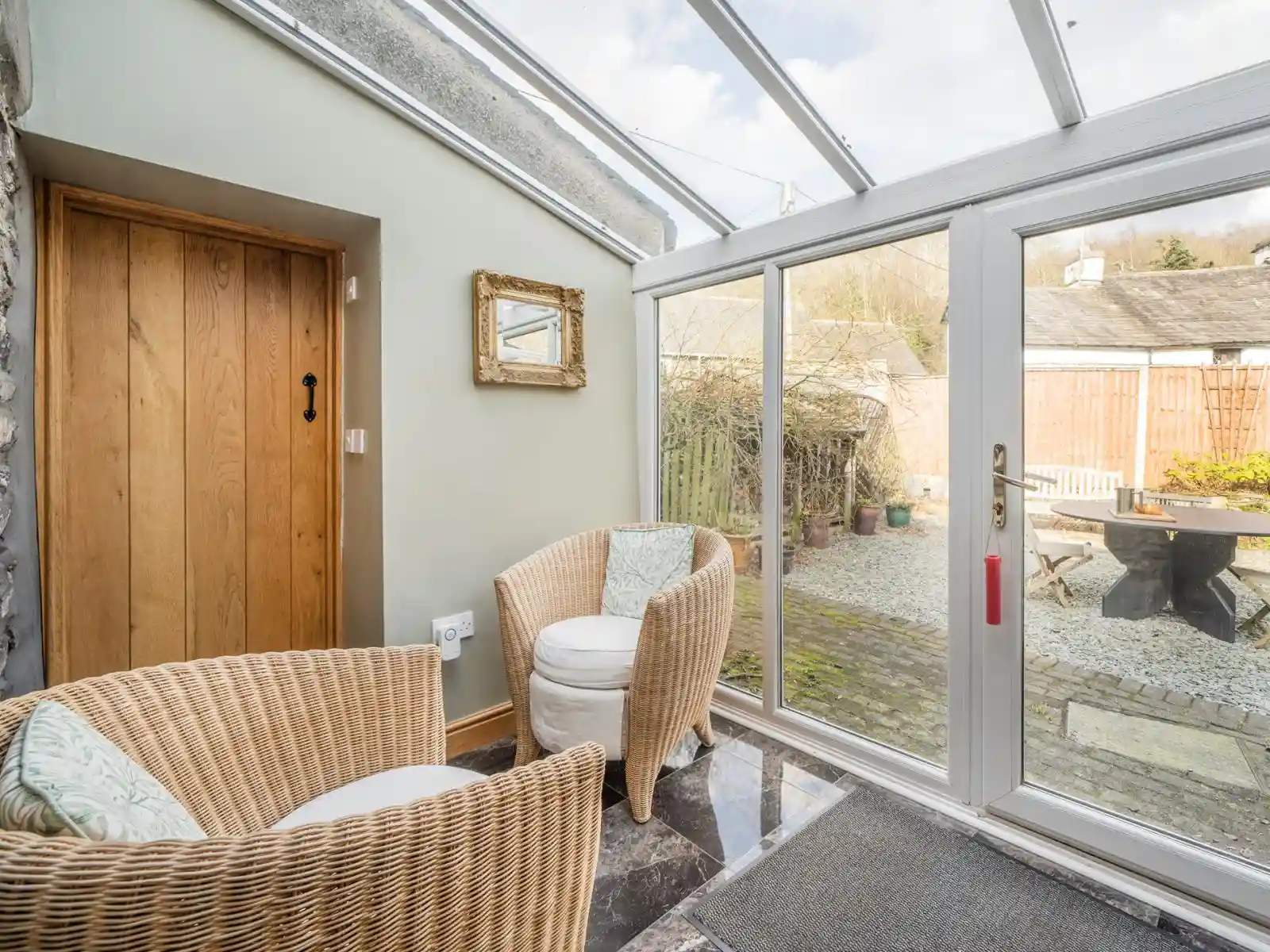A view of the conservatory with a glass roof and patio doors looking onto the garden