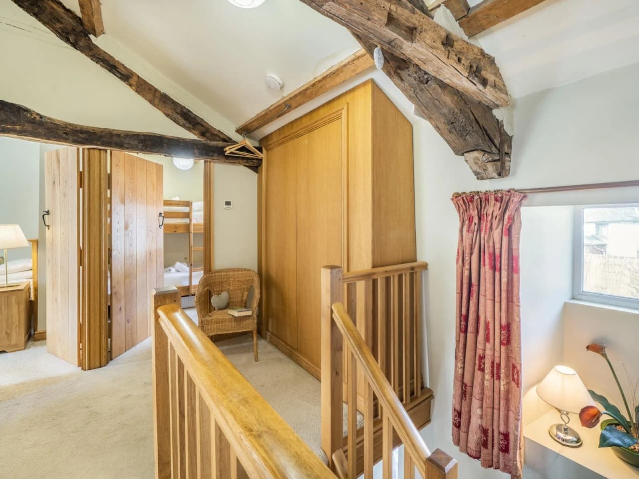 A view of the upstairs landing with exposed ceiling joists and beautiful wood work on the stair bannisers