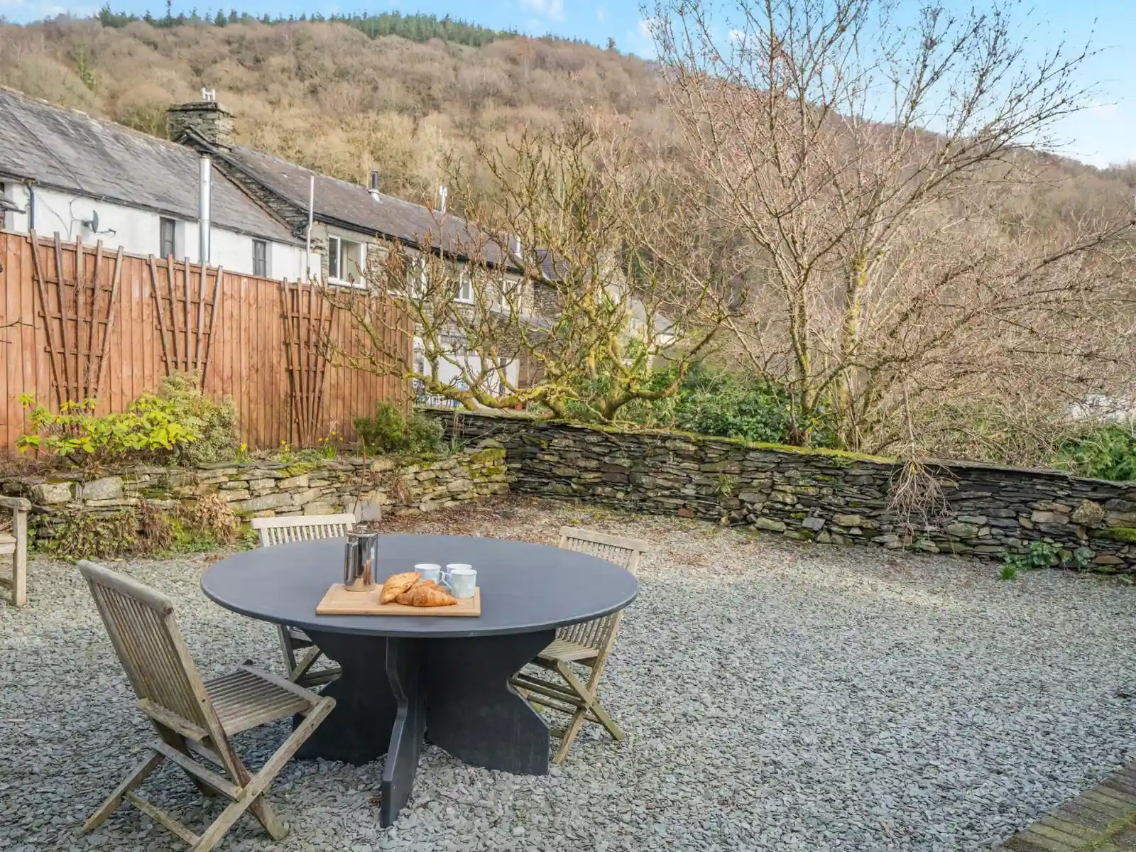 A view of the private back garden with beautiful dry stone walls and overhanding trees looking up into the forrest