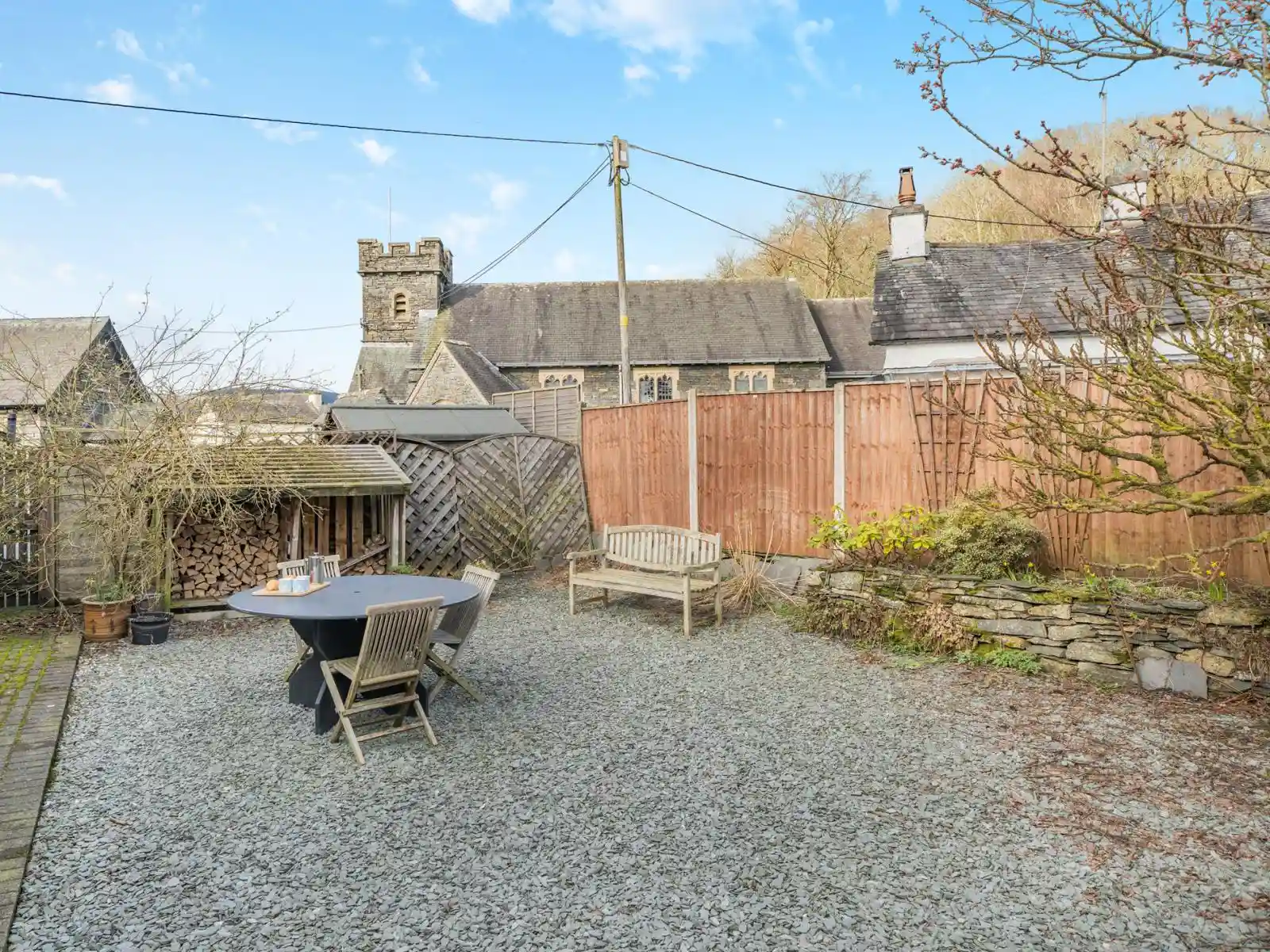 A view of the back garden, outdoor dining table and village church in the background